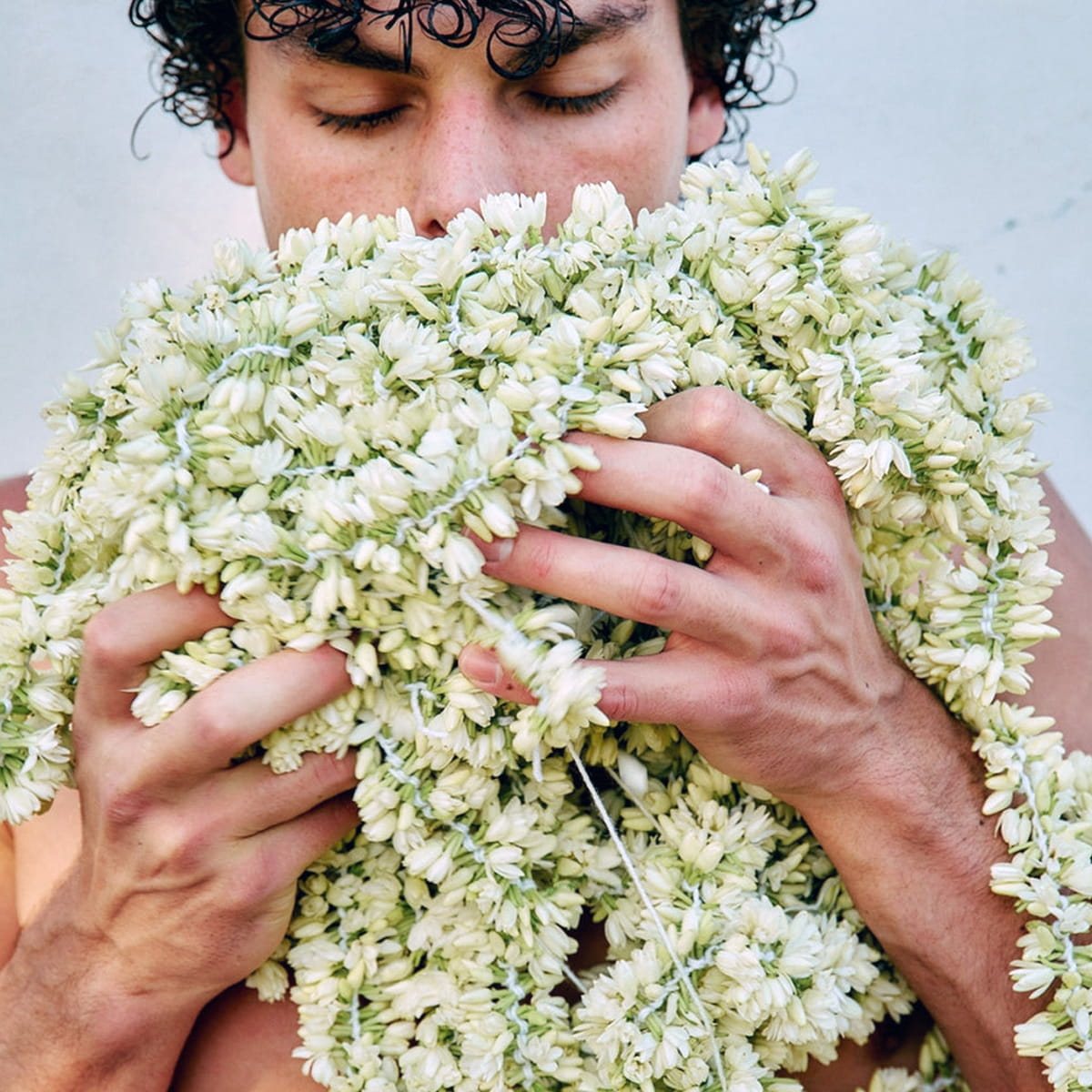 Man smelling and holding a large bunch of jasmine