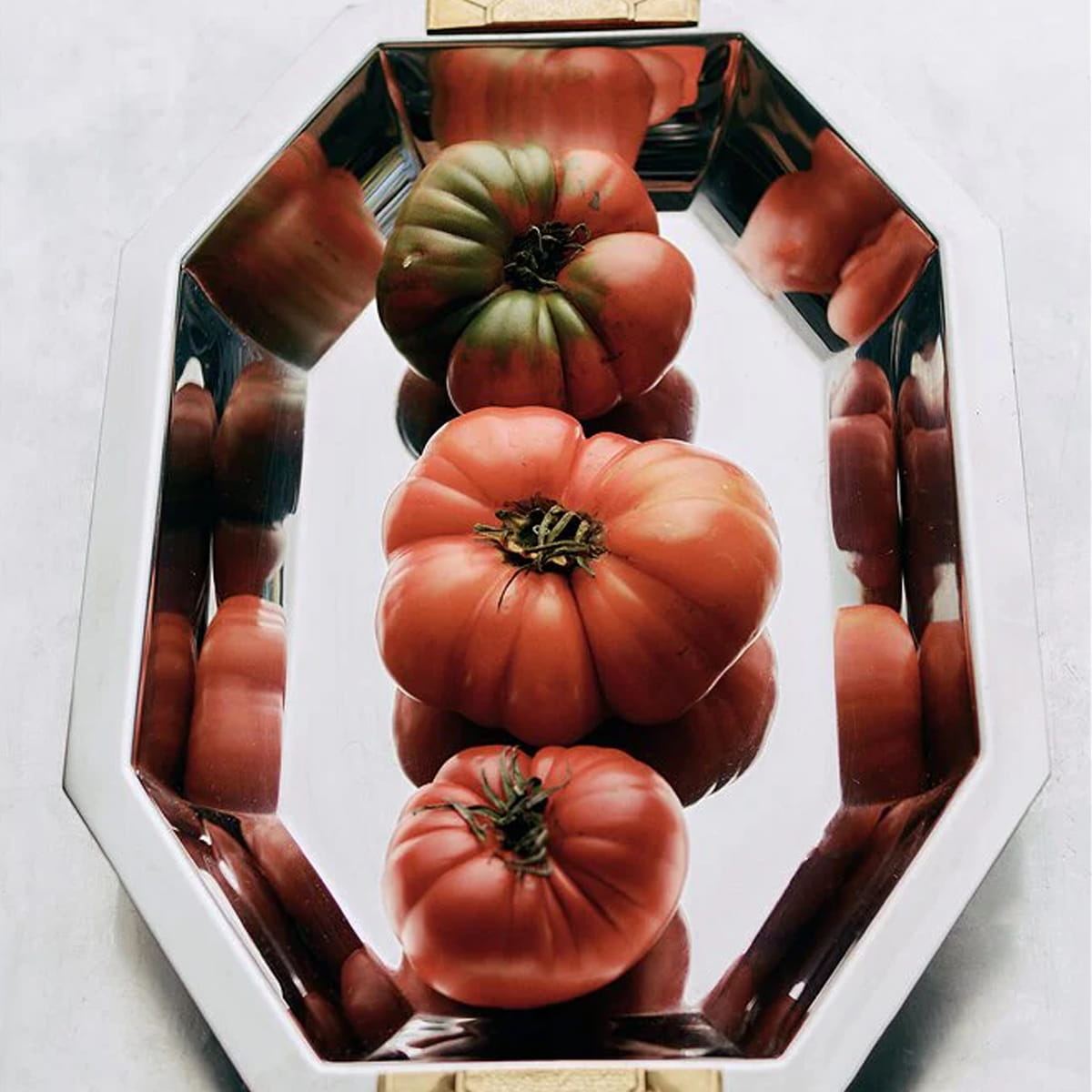 Decorative mirrored tray with three heirloom tomatoes.