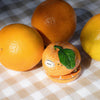 Nach Orange Stapler (1 pc) - product shown on gingham cloth next to other oranges.