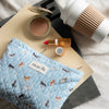 Nach Cats & Dogs Quilted Striped Pouch (1 pc) - product shown on top of magazines next to lipstick, coffee, and blush. 