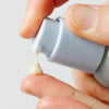 Close up of hand holding Ursa Major Sunny Start Eye Serum (0.5 oz) with cream being squeezed out on fingertip