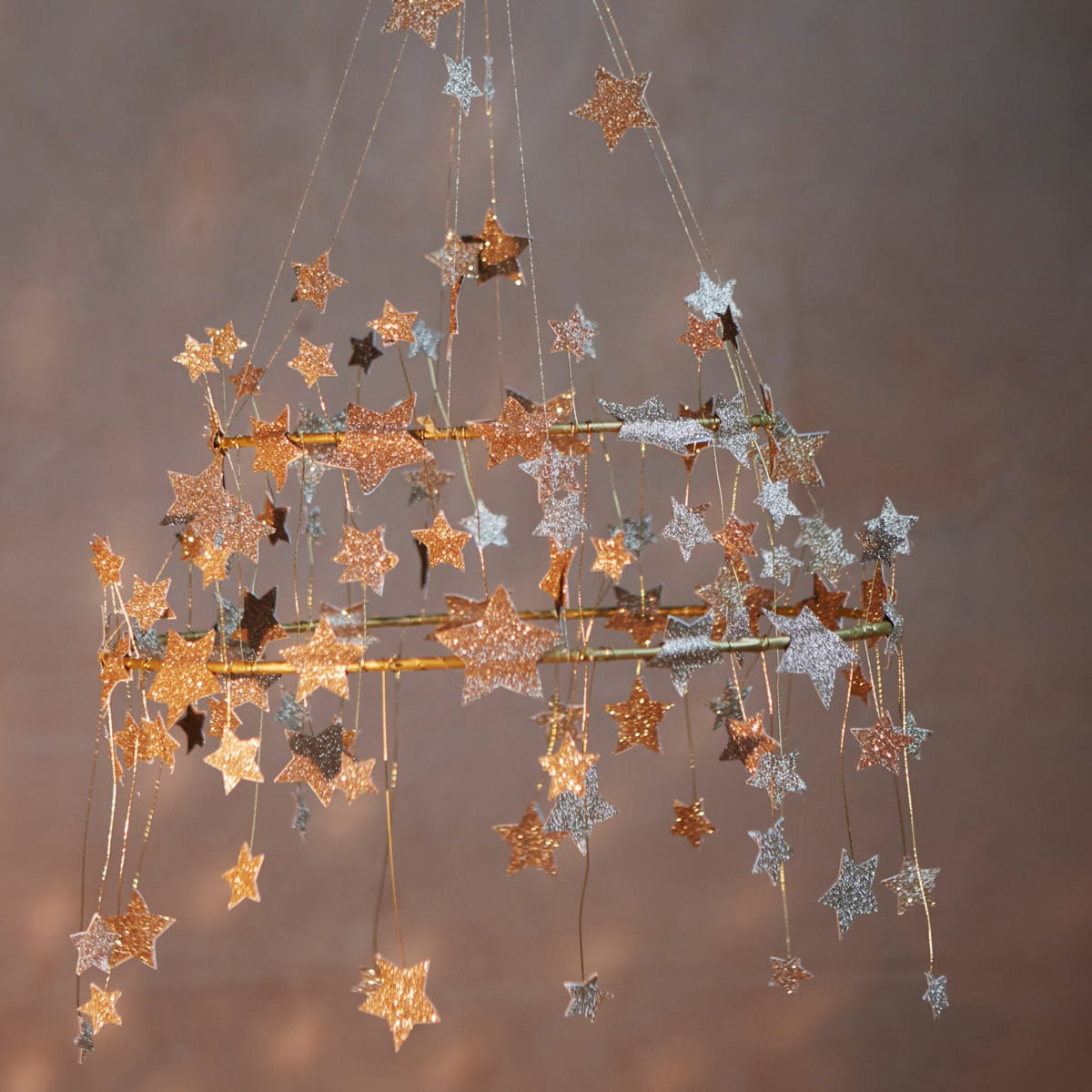 Meri Meri Gold Sparkle Star Chandelier (1 pc) - product shown in front of dark beige background. 