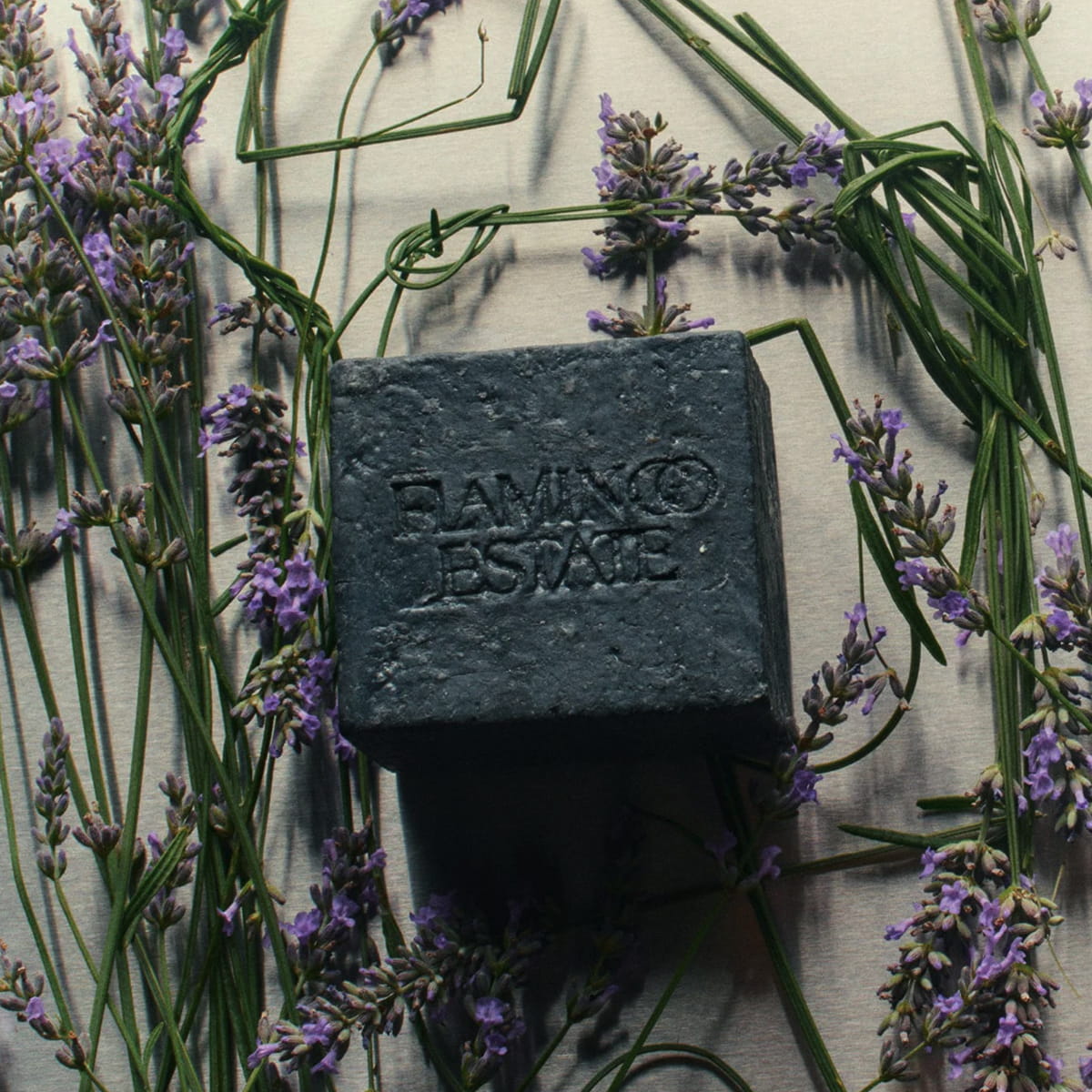 Flamingo Estate Lavender Activated Charcoal Soap Brick (340 g) - product shown with lavender flavors behind it.