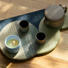 ROEN Candles Hakone Scented Candle (8 oz) - product shown on table mat with tea cups and tea kettle.