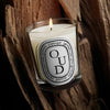 Diptyque Oud Classic Candle (190 g) - product shown in front of wood. 