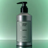 Lifestyle shot of Flamingo Estate Rosemary Clary Sage Shampoo (355 ml) against a green background