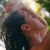 Woman taking a shower outdoors using Flamingo Estate Rosemary Clary Sage Conditioner (355 ml)