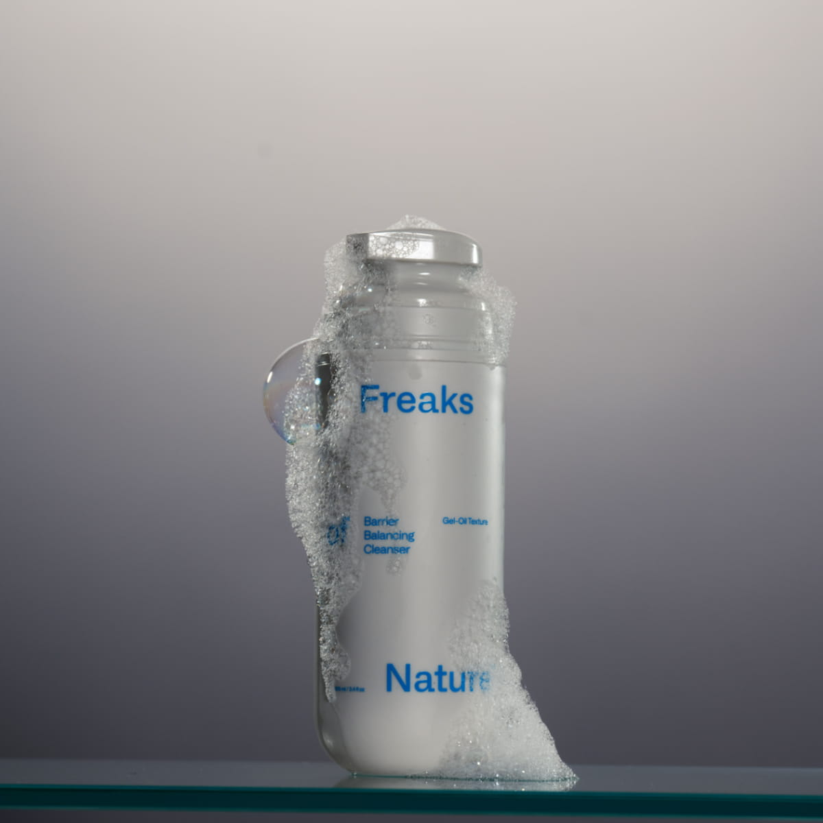 Freaks of Nature Barrier Balancing Cleanser (3.4 oz) sitting on a glass shelf with suds around bottle
