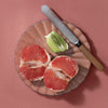 Cleo+Coco Body & Hair Powder - Grapefruit Bergamot (25 g) - Sliced grapefruit and lime on a glass plate with a knife against a pink background
