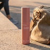 Cleo+Coco Body & Hair Powder - Grapefruit Bergamot (25 g) - on a concrete surface next to a brown bag.