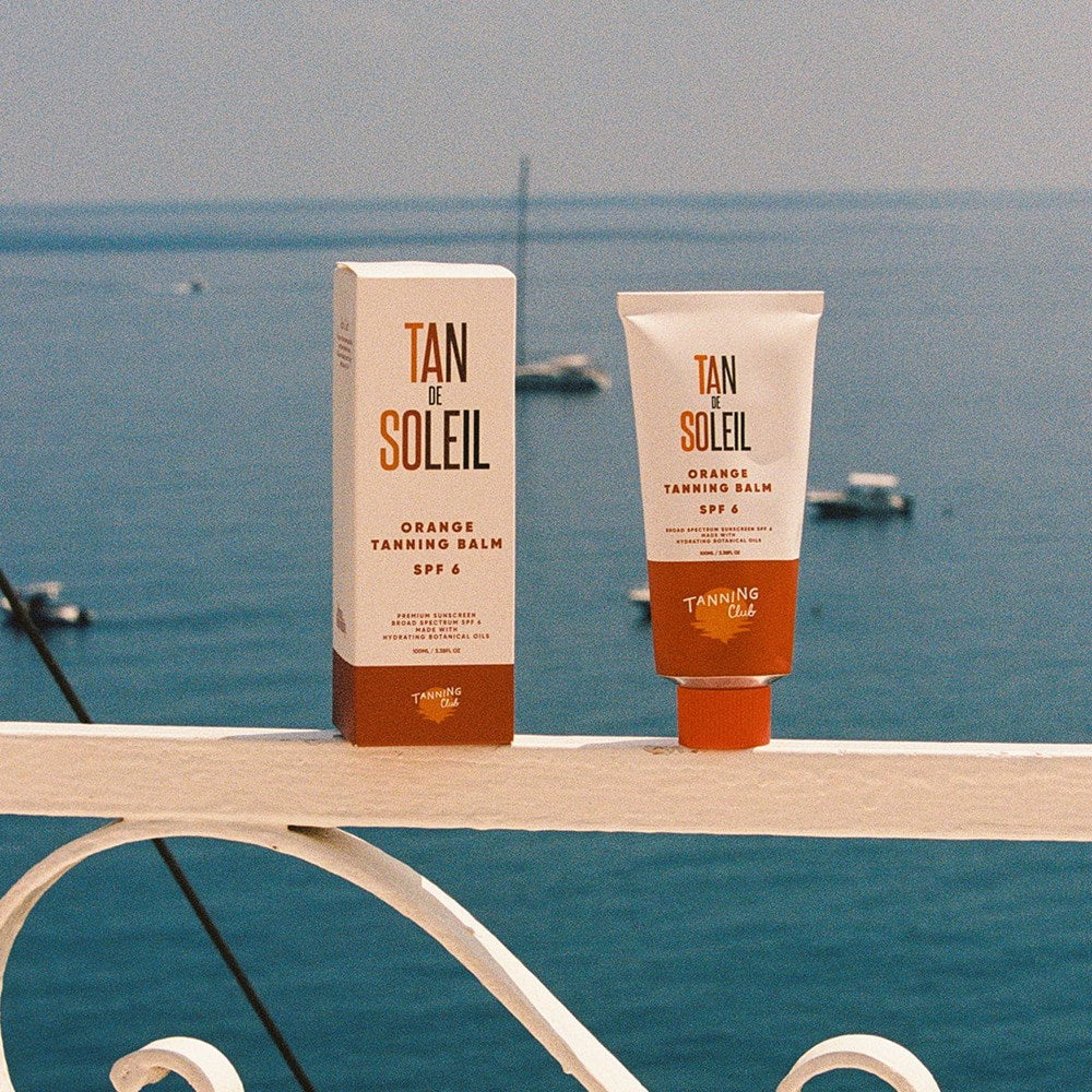 Tanning Club Tan de Soleil Orange Tanning Balm SPF 6 (3.38 oz) with a scenic ocean background