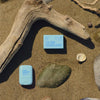 DUNE Suncare The Melt Stick (20.24 g) - product shown on beach with packaging. 