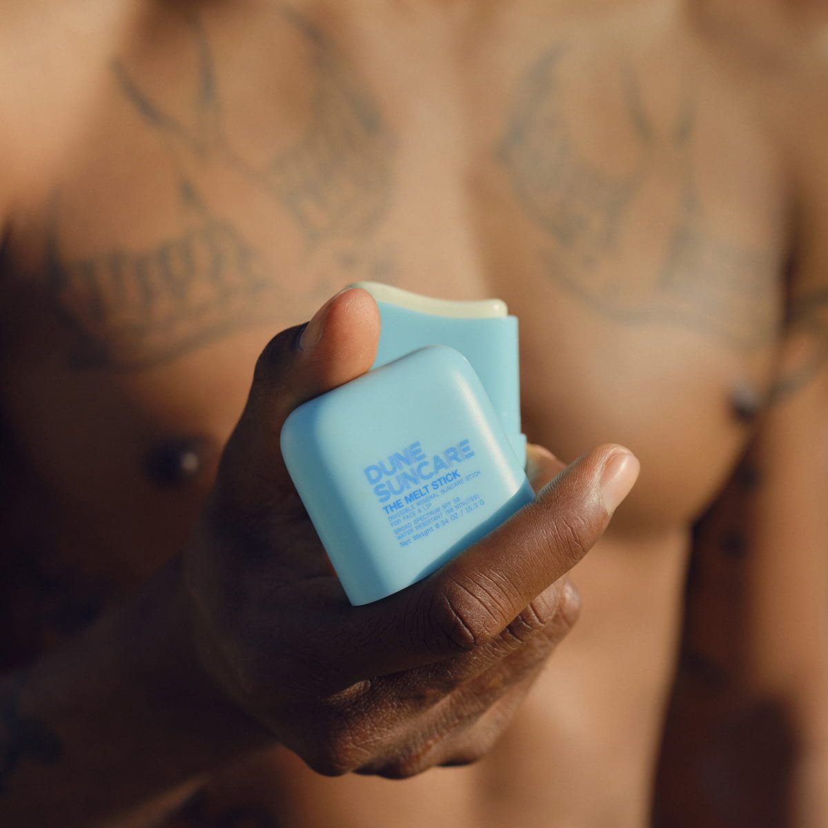 DUNE Suncare The Melt Stick (20.24 g) - product shown being held by model. 
