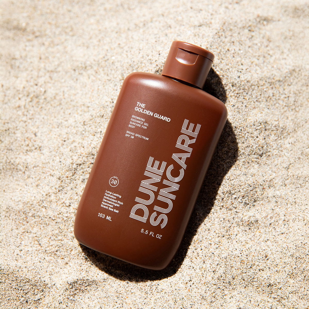 DUNE Suncare The Golden Guard (163 ml) - product shown in sand. 