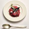 Flamingo Estate Sunny Side Up Recipe Book (1 pc) - A plated food dish on a textured off-white ceramic plate with a silver spoon below, photographed on a clean light background.