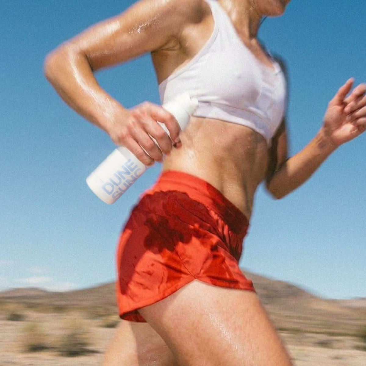 DUNE Suncare The Sporto Spray (148 ml) - Person running outdoors with product in hands.