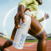 DUNE Suncare The Sporto Spray (148 ml) - person running with product in hand.