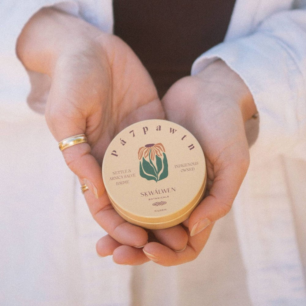 Sḵwálwen Botanicals Pá7pawtn Nettle and Arnica Salve (1.81 oz) - product shown being held in hands. 