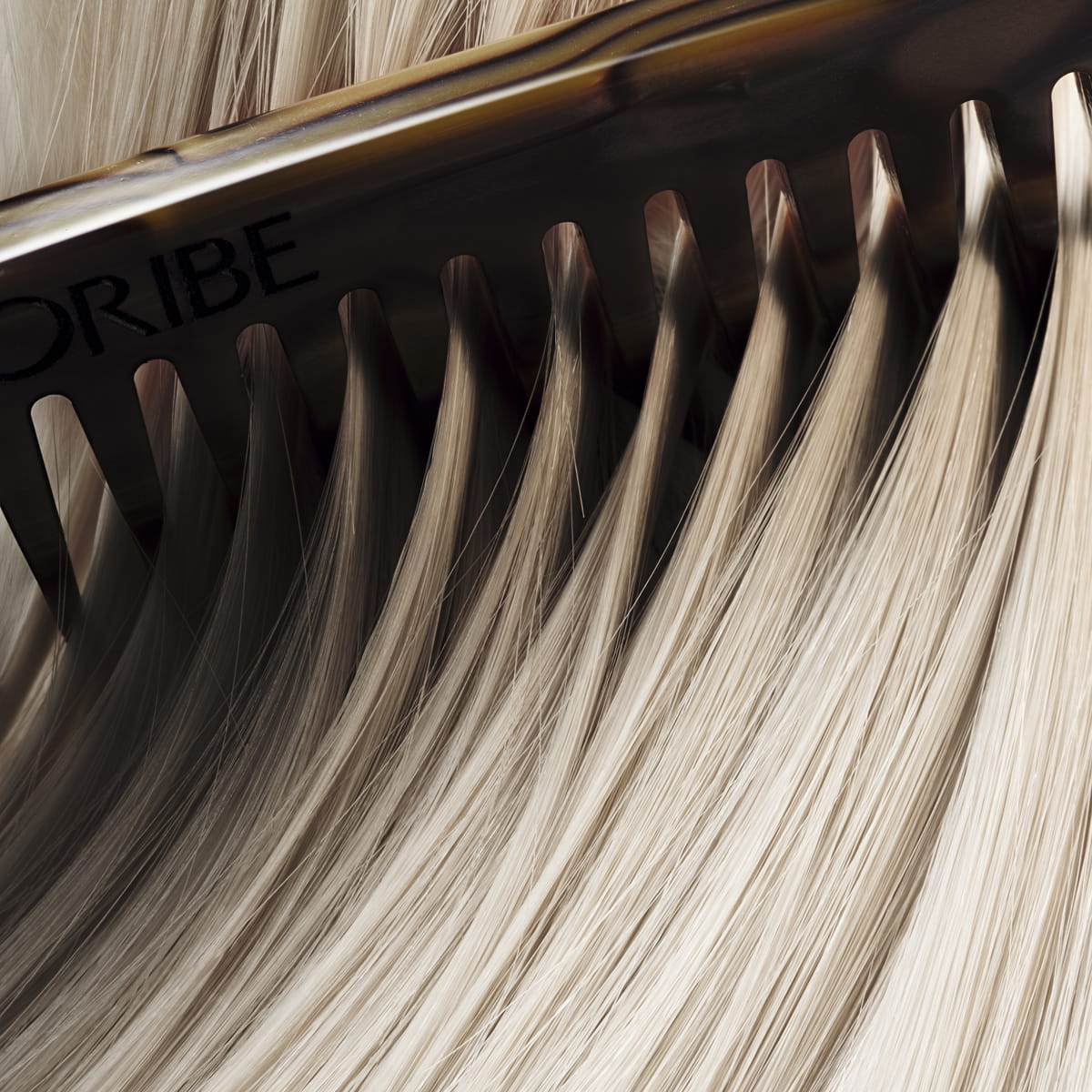 Oribe Hair Alchemy Bond Building Elixir (3.4 oz) - hair shown close up with an Oribe comb.