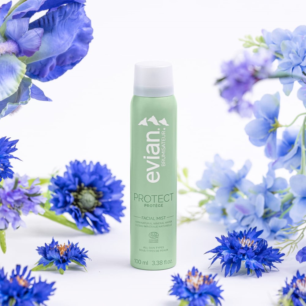 Evian Protect Facial Mist (100 ml) - product shown being surrounded by flowers.