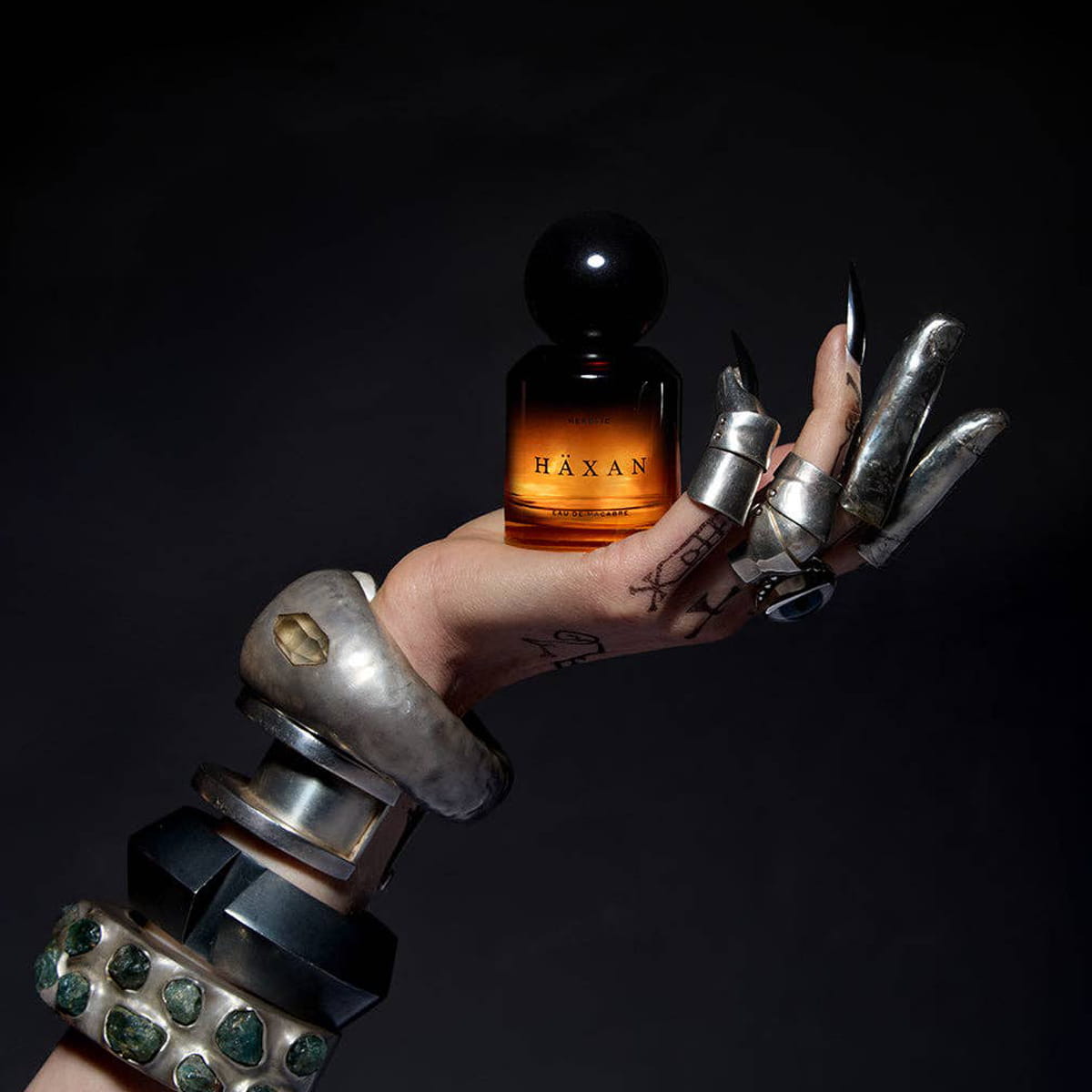 Heretic Parfum Haxan Eau de Macabre (30 ml) - product shown being held by armored hand.