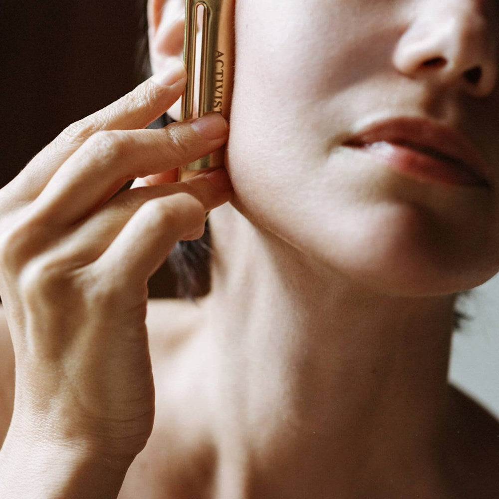 Activist Brass Tube Press (1 pc) - product shown being used on face.
