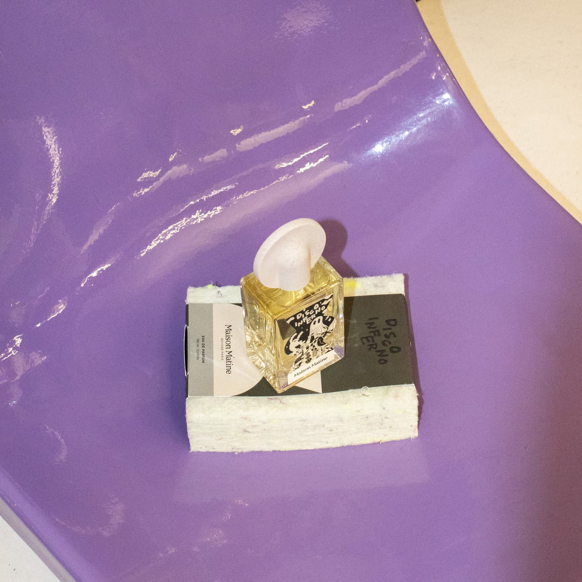 Lifestyle shot of Maison Matine Disco Inferno Eau de Parfum (100 ml) sitting on top of packaging