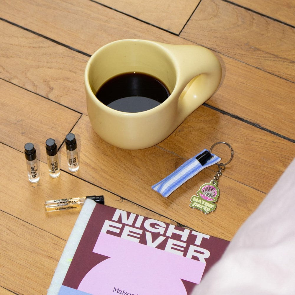 Lifestyle shot of Maison Matine Night Fever Discovery Set (5 x 2 ml) with cup of coffee in the background