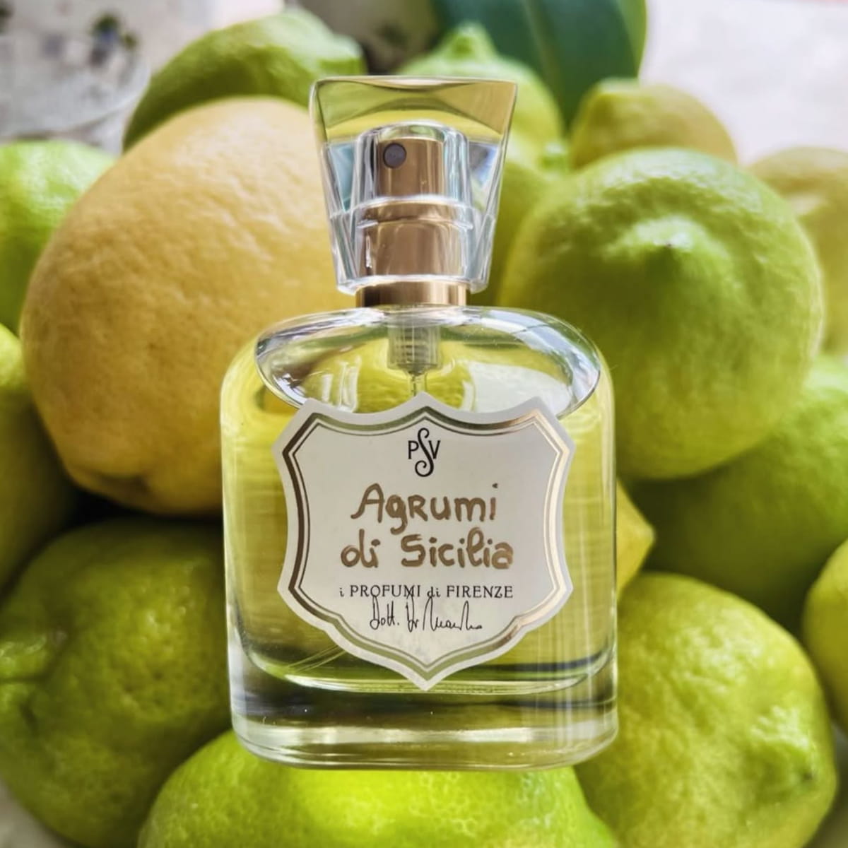 Lifestyle shot of i Profumi di Firenze Agrumi di Sicilia Eau de Parfum (50 ml) set against a background of green and yellow lemons.