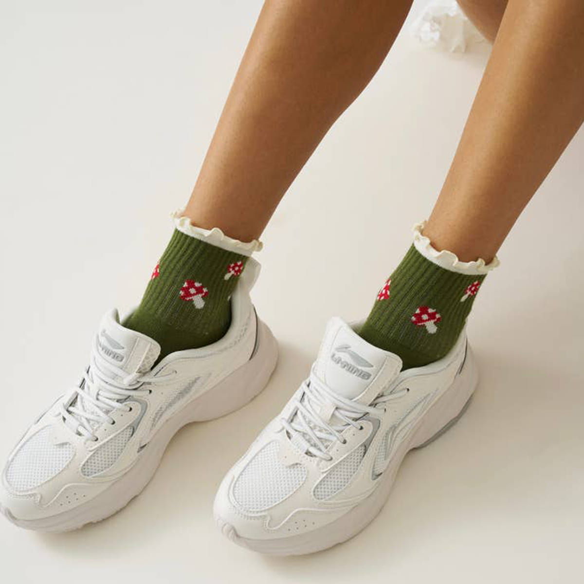 Model wearing Effortless Club Mushroom Ruffle Grip Socks (1 pair) with athletic shoes