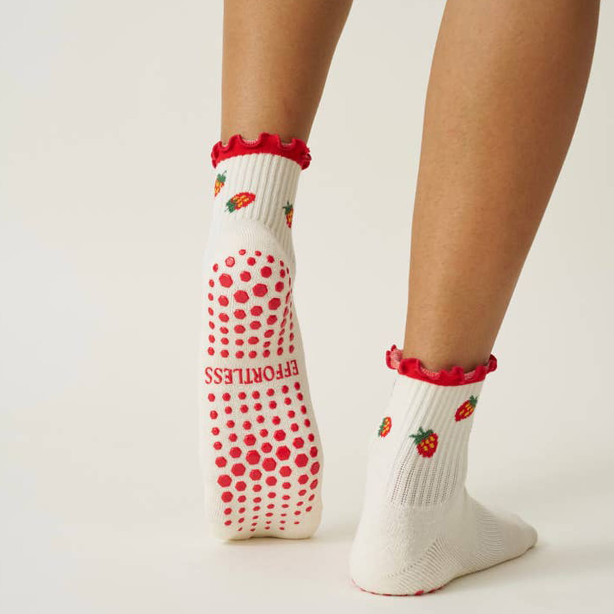 Model wearing Effortless Club Strawberry Ruffle Grip Socks (1 pair) showing partial side view and back side of sock