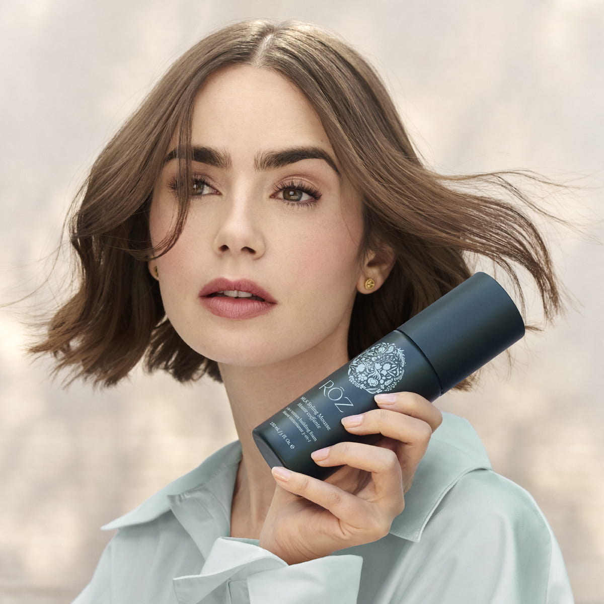 Model with short hair holding Roz Milk Styling Mousse (150 ml)