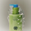 Close up of BASE-K The Matcha Rinse Thickening Shampoo (266 ml) surrounded by clear bubbles