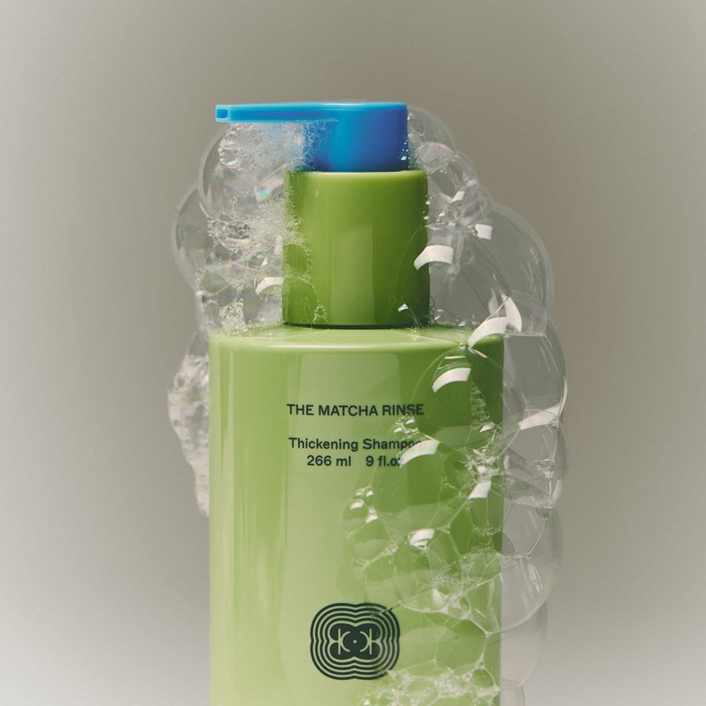 Close up of BASE-K The Matcha Rinse Thickening Shampoo (266 ml) surrounded by clear bubbles