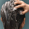 Close up of woman applying BASE-K The Matcha Rinse Thickening Shampoo to hair