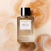 Essential Parfums Ambre Latte by Jordi Fernandez (100 ml Refillable) - product shown on top of a coffee background.