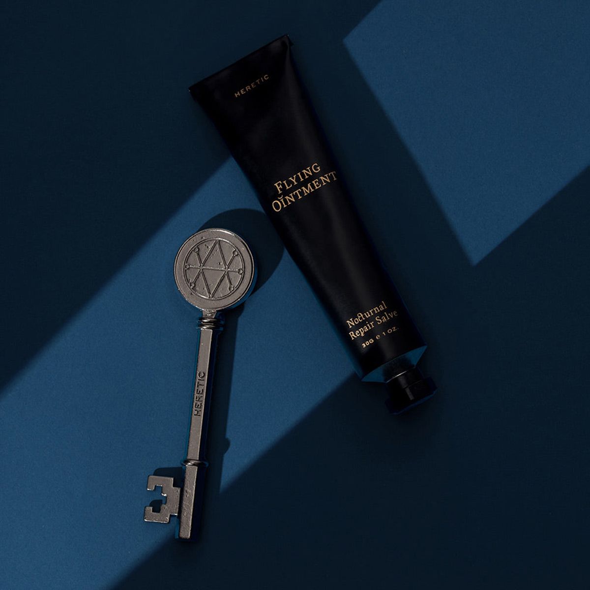 Heretic Parfum Flying Ointment (30 g) - product shown on blue background.