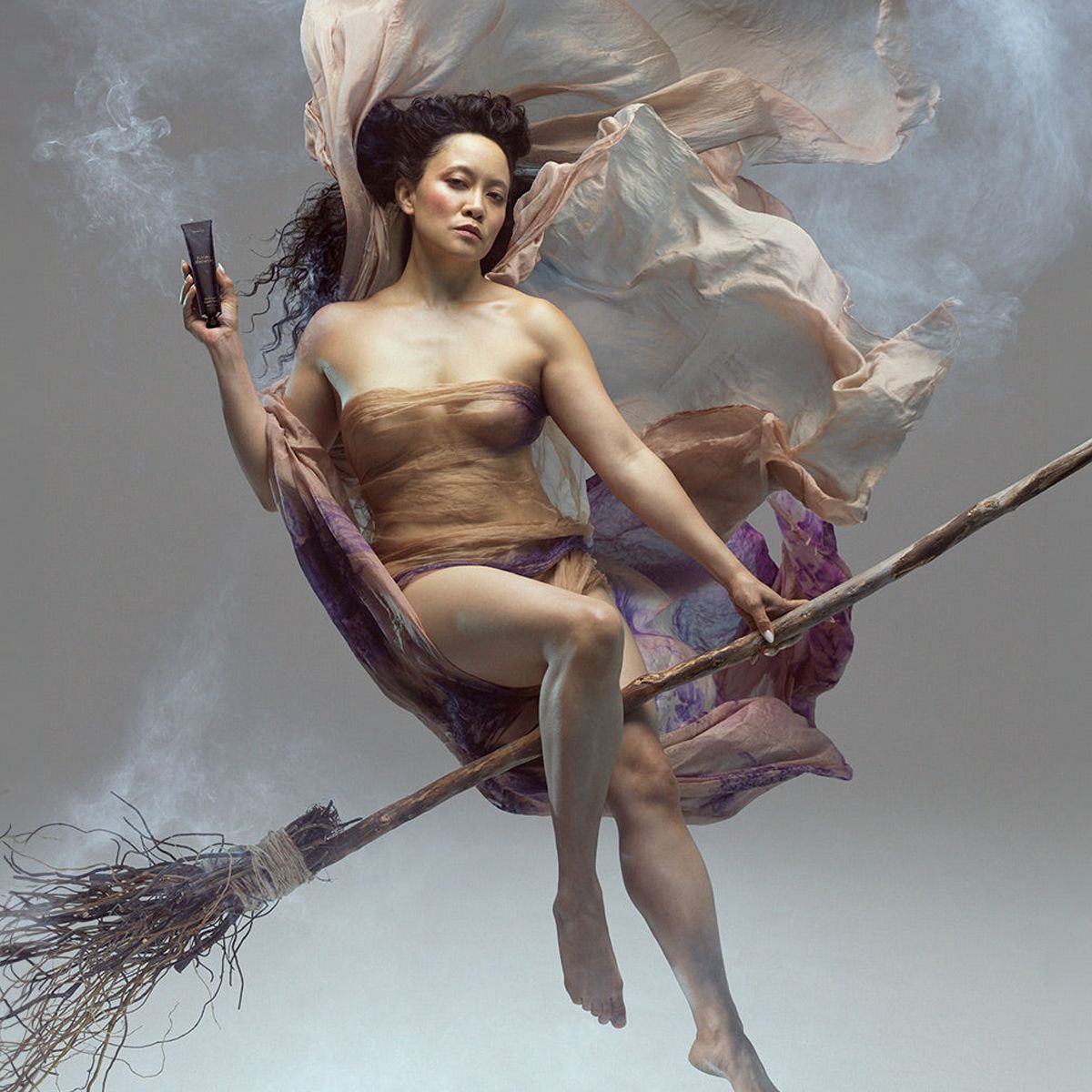 Heretic Parfum Flying Ointment (30 g) - product shown being held by model on broomstick. 