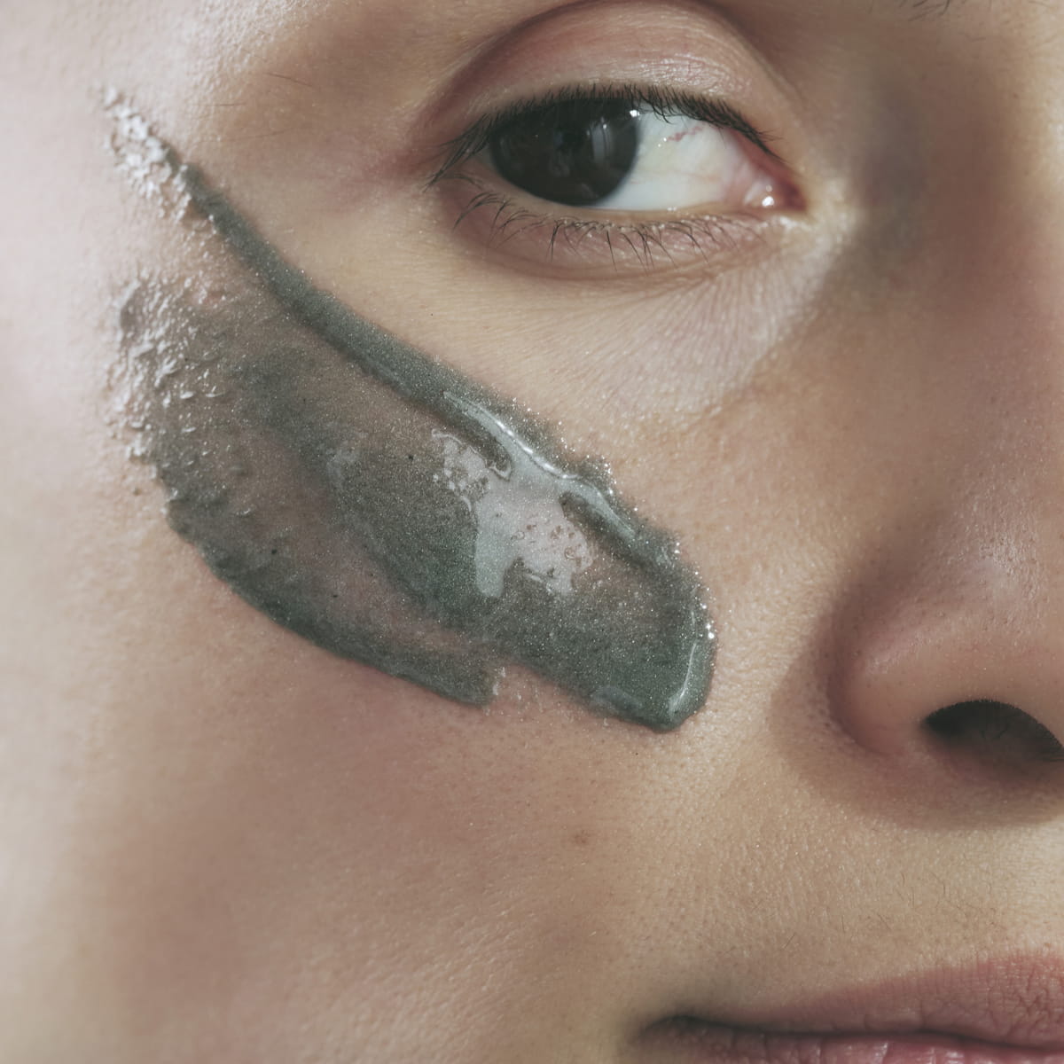 Close-up of a person's face with Activist Manuka Honey Glacial Clay Mask applied under the eye.