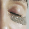 Close-up of a person's eye with Activist Manuka Honey Glacial Clay Mask applied beneath the closed eyelid.