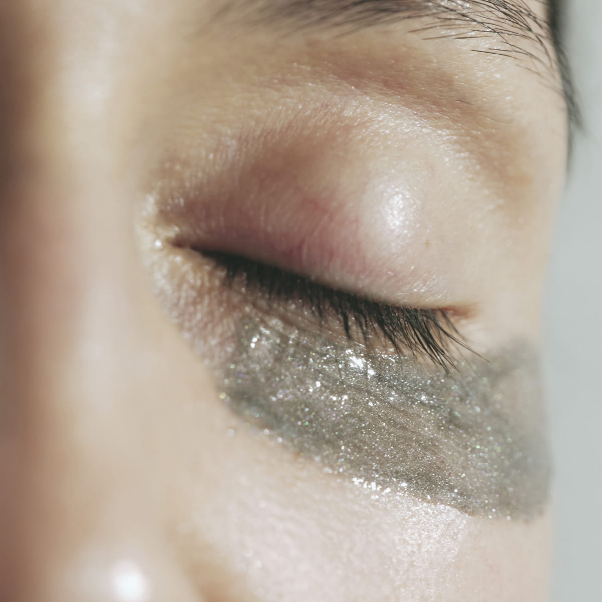 Close-up of a person's eye with Activist Manuka Honey Glacial Clay Mask applied beneath the closed eyelid.