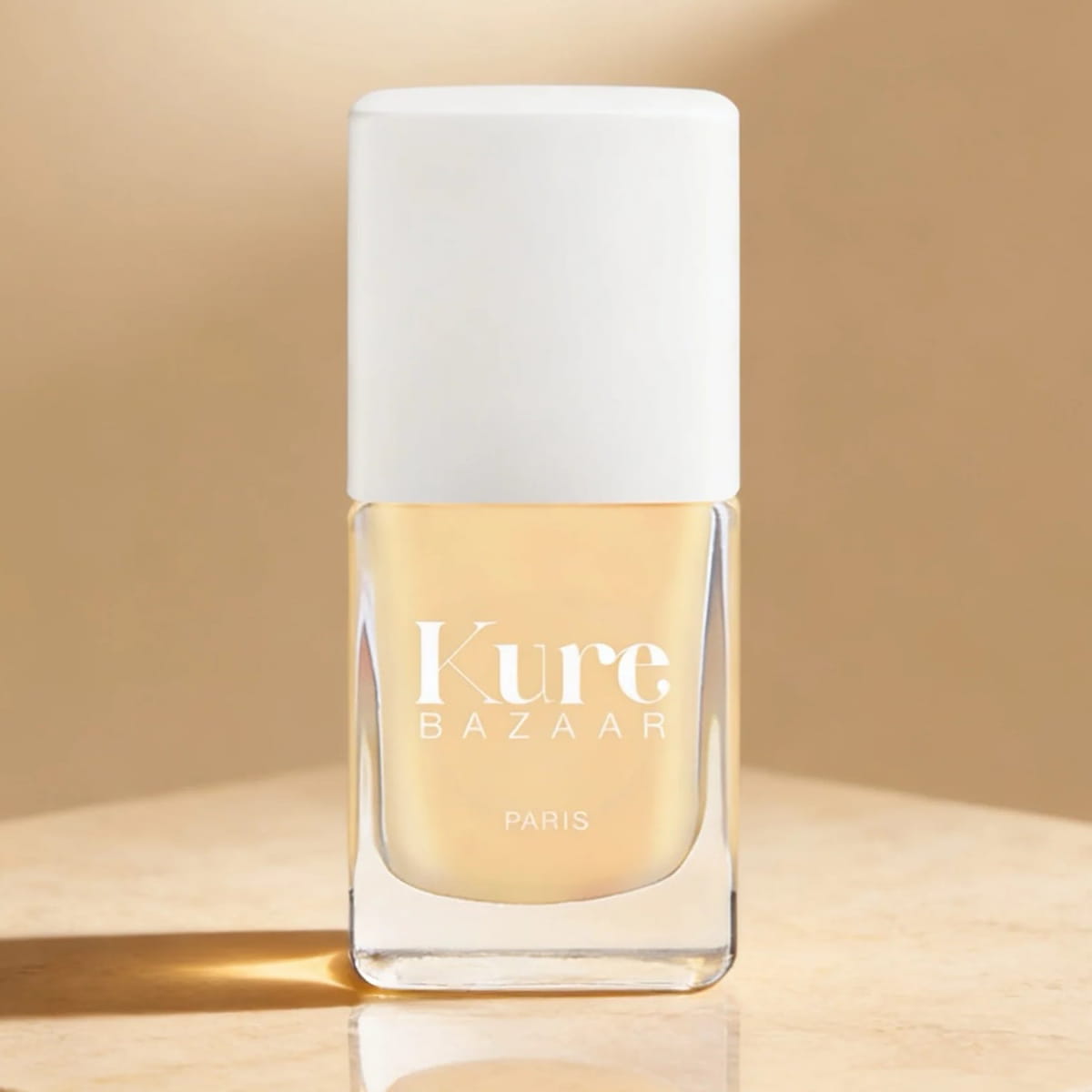 Kure Bazaar Nail Lacquer - Butter Cream (10 ml) - product shown on creme background. 
