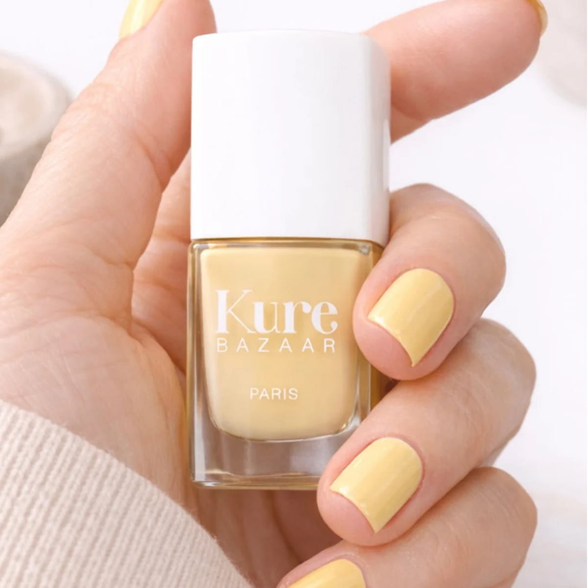 Kure Bazaar Nail Lacquer - Butter Cream (10 ml) - product shown being held.