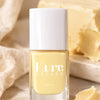 Kure Bazaar Nail Lacquer - Yellow Butter (10 ml) - product shown in front of butter.