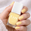 Kure Bazaar Nail Lacquer - Yellow Butter (10 ml) - product shown being held.