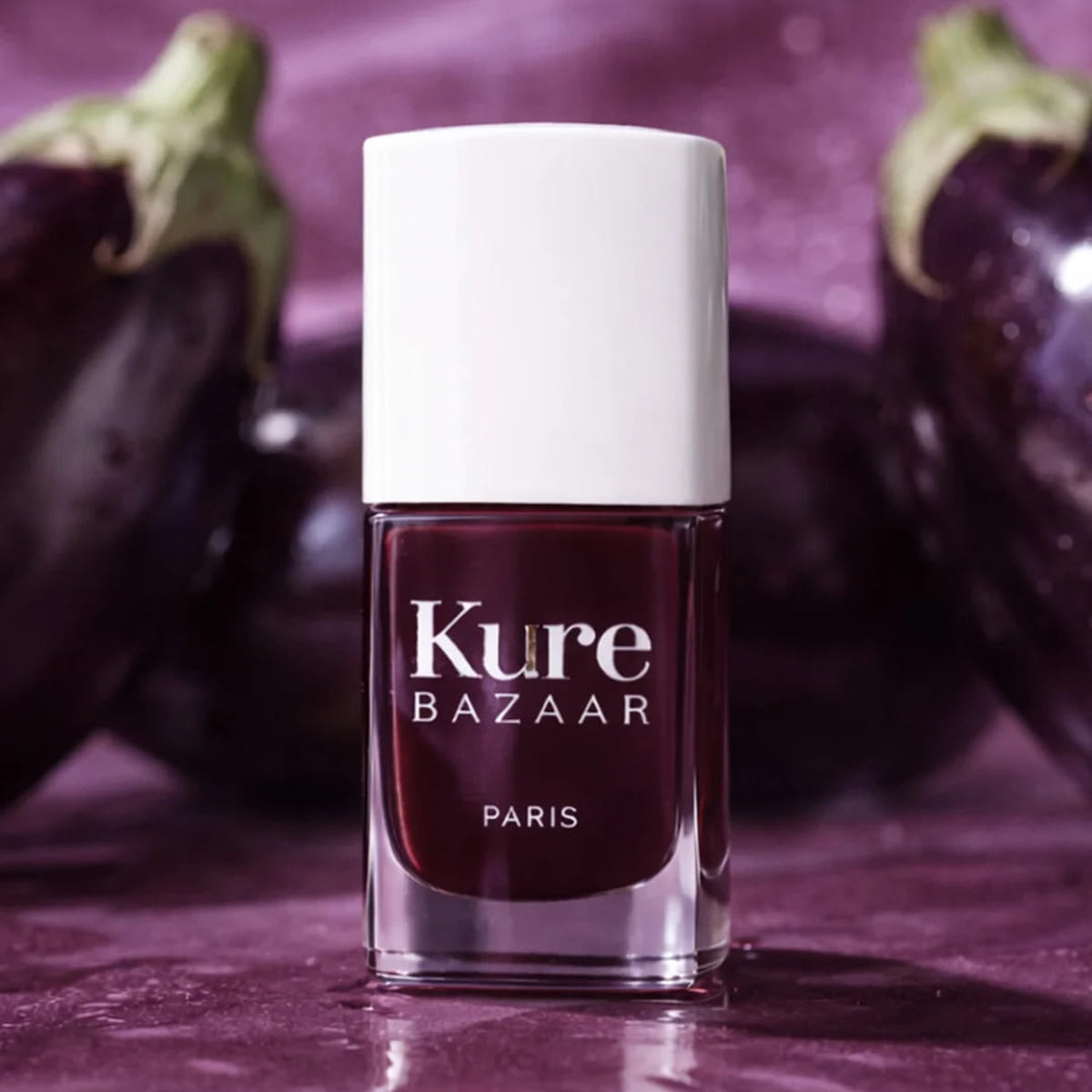 Kure Bazaar Nail Lacquer - Burgundy (10 ml) - product shown in front of eggplants.