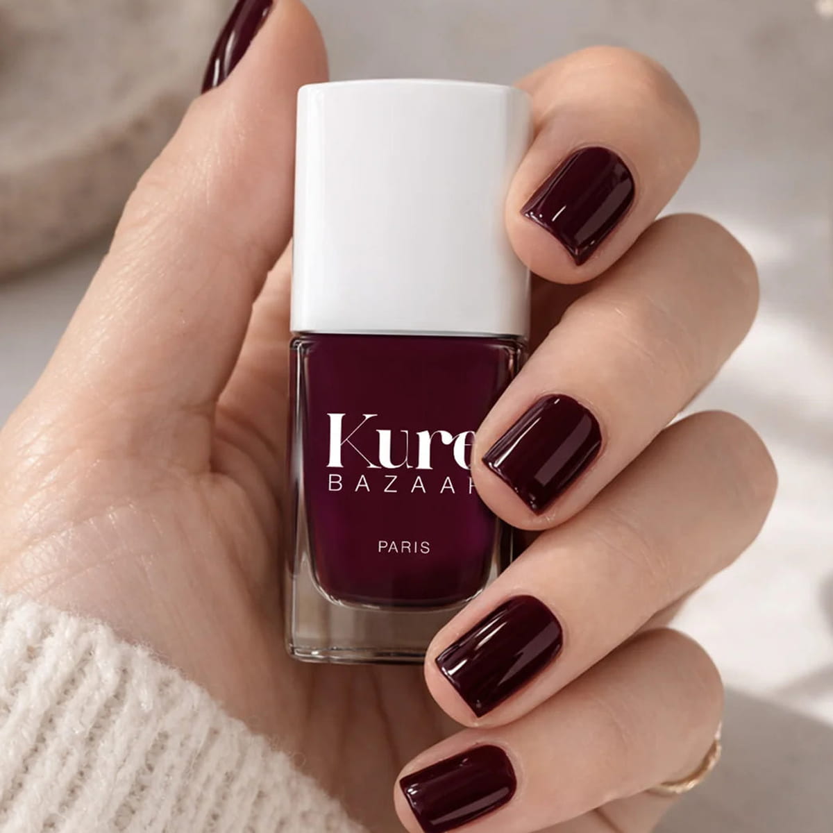 Kure Bazaar Nail Lacquer - Burgundy (10 ml) - product shown being held.