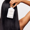 Rahua Rebalance Conditioner (275 ml) - product shown being held by model. 