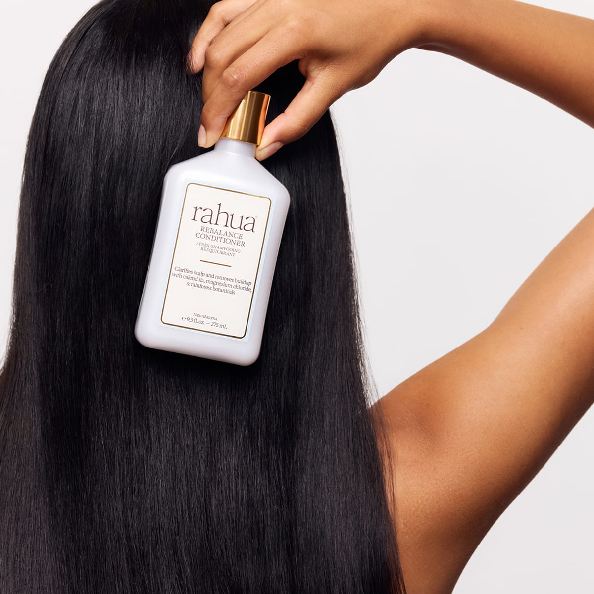 Rahua Rebalance Conditioner (275 ml) - product shown being held by model. 