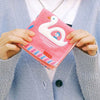 A person holding a folded Hightide Hand Towel - Swan Boat (1 pc) 